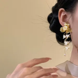 Detail shot of French vintage golden flower tassel earrings with white pearls on ear.