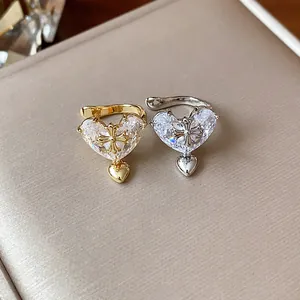 Pair of zircon heart-shaped ear cuffs with cross detail in gold and silver finish.