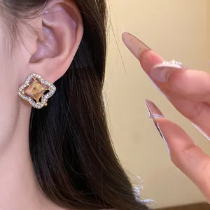 Detail view of a luxury gold-plated stud earring with a champagne crystal on model ear