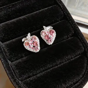 Macro detail of strawberry stud earrings with pink and clear rhinestones on velvet