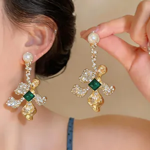 Detailed close-up of vintage flower earrings featuring pearls, rhinestones and a green gemstone.