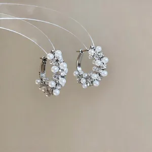 Primo piano di eleganti orecchini a cerchio con perle bianche e dettagli in zircone lucido