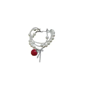 Elegant multi-layer pearl bracelet featuring a zircon bow and vibrant red apple charm