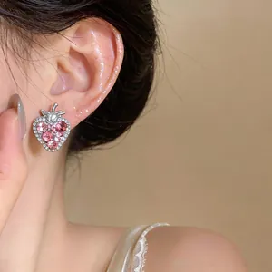 Close-up of a sparkling pink crystal strawberry earring worn on the ear.