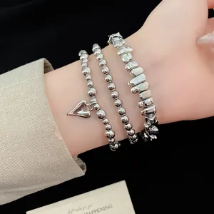 Dettaglio di braccialetti d'argento a perline con ciondolo a cuore sul polso