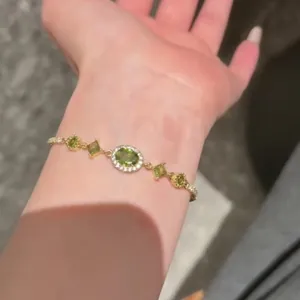 Elegante bracciale placcato oro 18 carats con zircone ovale verde su un polso