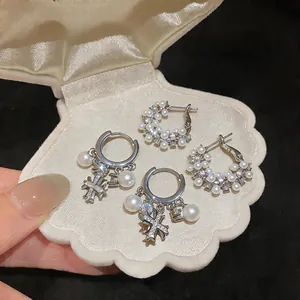 Dettaglio di eleganti orecchini a cerchio con zirconi e perle in un portagioie di velluto.