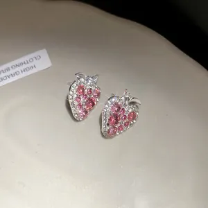 Close-up detail of sparkling pink strawberry stud earrings with rhinestones and silver pins