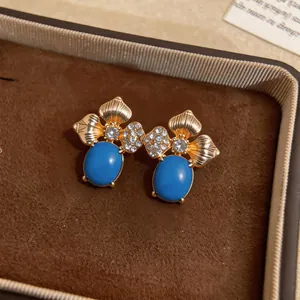Close-up detail of vintage flower stud earrings with oval blue stones and crystals
