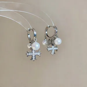 Dettaglio di orecchini a cerchio in argento con croce in zircone e perle