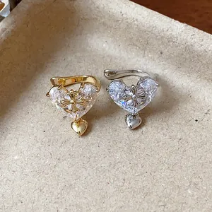 Detail shot of gold and silver heart ear cuffs with zircon and gothic cross motif.
