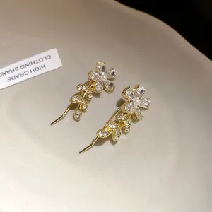 Close-up of elegant gold flower earrings with crystals and pearls.