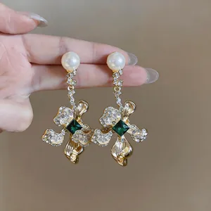 Detailed view of vintage flower earrings with central green gemstone and white pearls.