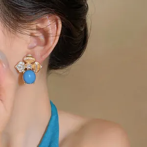 Detail view of a gold floral earring with turquoise stone and sparkling rhinestones
