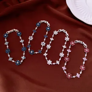 Detail of four flower-shaped cubic zirconia bracelets in various colors on brown fabric