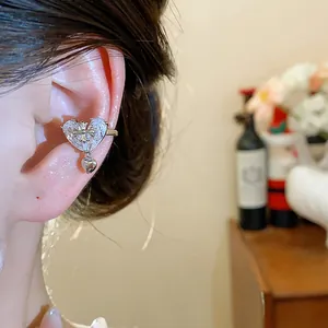 Detailed view of an 18k gold plated heart ear cuff with zircon and cross accent