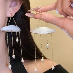 Close-up of shell tassel earrings with freshwater pearls on gold chains