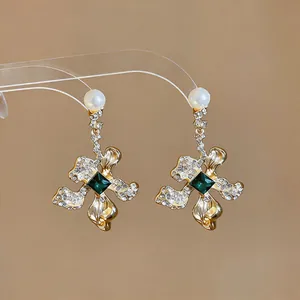 Close-up of vintage floral gold earrings with green gemstone, rhinestones and pearls.
