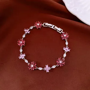 Close-up detail of silver-toned metal bracelet with pink and red zircon flowers