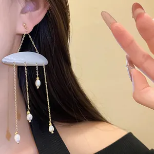Close-up of elegant silver needle tassel earrings with shell and freshwater pearls