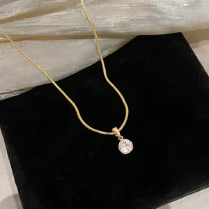 Detailaufnahme einer eleganten Goldkette mit funkelndem runden Zirkonia-Anhänger.
