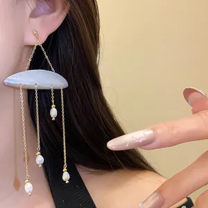 Close-up of elegant freshwater pearl tassel earrings with a shell cloud design on model