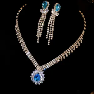 Elegant blue pear-shaped zirconia necklace and dangling earrings set on black background.