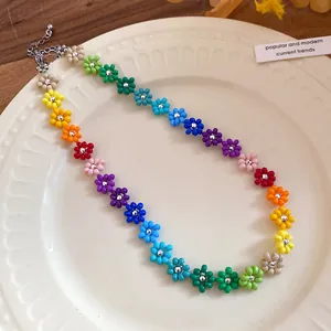 Detail view of a bohemian colorful handmade beaded flower necklace on a white ceramic plate