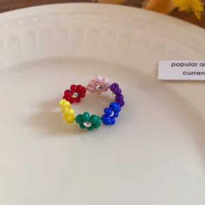 Close-up of bohemian colorful seed bead flower ring on a white ceramic plate background