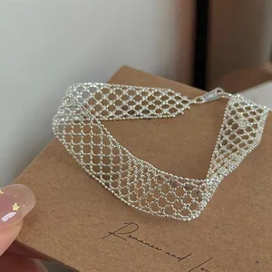 Detailed macro view of an elegant silver hollow mesh grid bracelet on a brown display card