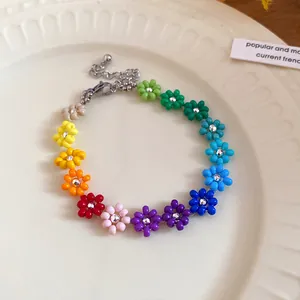 Macro view of a bohemian rainbow seed bead flower necklace featuring a silver lobster clasp