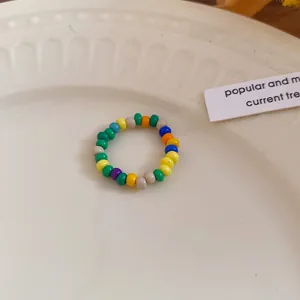 Detailed macro view of a bohemian colorful rice beaded ring displayed on a white plate