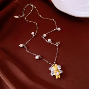 Detailed view of a yellow rabbit pendant necklace with pearls and zircon wings