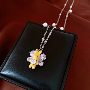 Detail of a yellow rabbit pendant necklace with pearls and sparkling zircons.