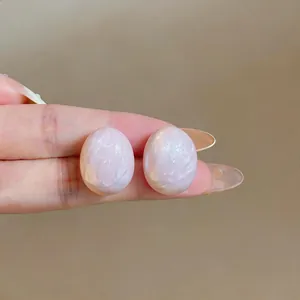 Primo piano di eleganti orecchini ovali rosa pallido con finitura perlata marmorizzata