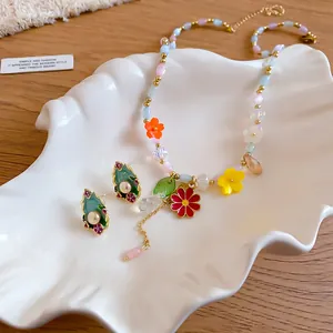 Dettaglio di collana a fiori estivi colorati con orecchini di perle in smalto.
