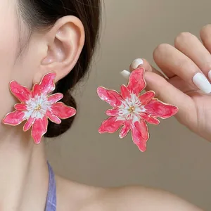 Vibrant pink and white enamel flower stud earrings with elegant golden trim on model