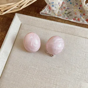 Dettaglio degli orecchini ovali in resina marmorizzata rosa su vassoio