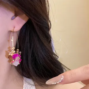 Orecchini a cerchio in oro stile etnico con pendenti in perline di pietra rosa su modella