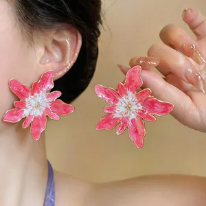 Macro close-up detail of oversized pink enamel flower stud earrings with gold edges
