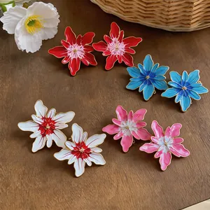 Detailed view of colorful oil-dropped flower stud earrings on a rustic wood surface