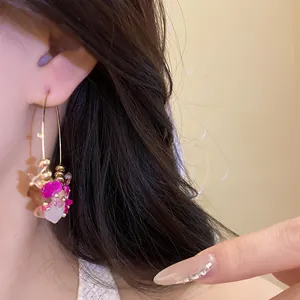 Primo piano di orecchini a cerchio in stile etnico con pietre rosa sull'orecchio
