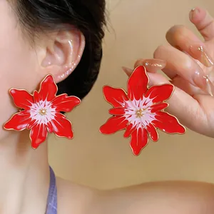Detail view of bold red enamel flower stud earrings with a stylish oversized design