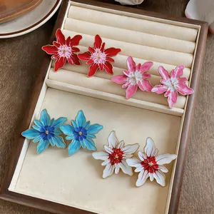 Detailed view of colorful enamel flower stud earrings arranged in a velvet jewelry tray