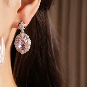 Dettaglio di un elegante orecchino a goccia ovale in zircone rosa indossato all'orecchio