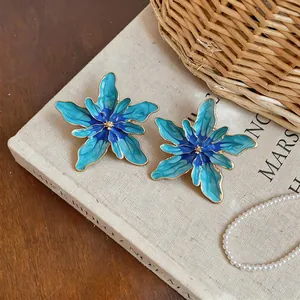 Detailed view of oversized blue gradient enamel flower earrings with gold edges