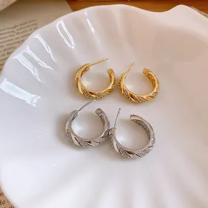 Macro view of gold and silver plated wheat hoop earrings with sparkling zircons