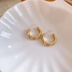 Close-up of 14k gold-plated twisted hoop earrings with micro-inlaid cubic zirconia