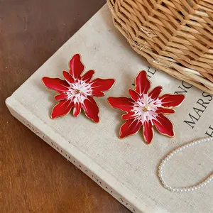 Detailed macro view of vibrant red and white enamel flower stud earrings with gold edges