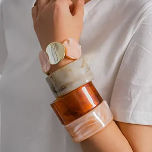 Gros plan détaillé de bracelets joncs en résine empilés et bracelet élastique marbré